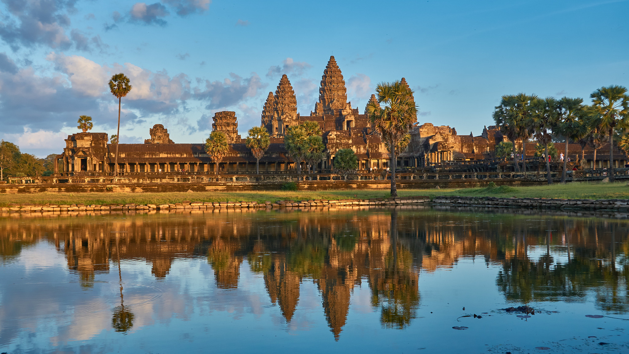 The Angkor Wat temple complex in Cambodia, with towers rising beyond water and stone causeways.